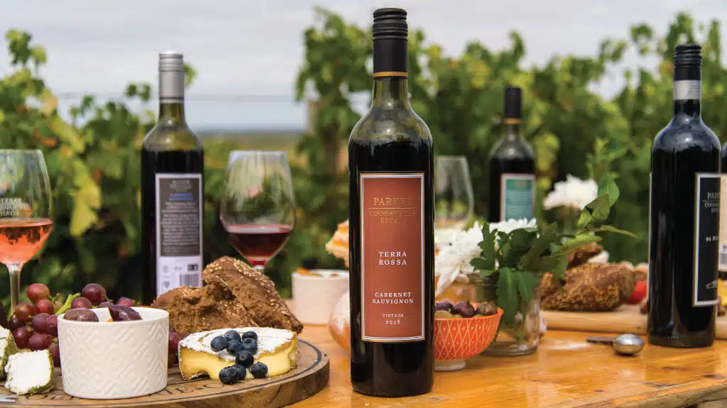 A selection of Limestone Coast wines on a table laden with delicious bread, cheese and fruit, Parker Coonawarra Terra Rossa Cabernet Sauvignon in the centre